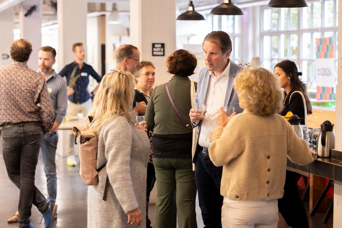 Meerdere mensen in gesprek op een congres Meerdere mensen in gesprek op een congres